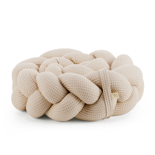 Τριπλή πάντα πλεξούδα σε μπέζ χρώμα από βαμβακερό ύφασμα waffle, με χειροποίητη λεπτομέρεια και ετικέτα Hebe Home – ιδανική για βρεφικό κρεβάτι.