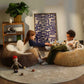Two children playing with dolls on bean bags in a cozy living room.